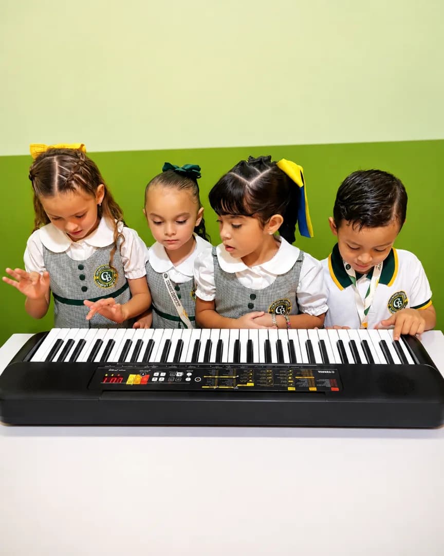 Niños en un aula tocando un teclado musical, colaborando y aprendiendo juntos con entusiasmo.
